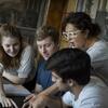 A teacher and four students discuss their work.