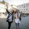 A professor and student with cameras around their necks observe their surroundings in an Italian piazza.