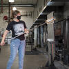 student inserting glass blowing instrument into the kiln. 